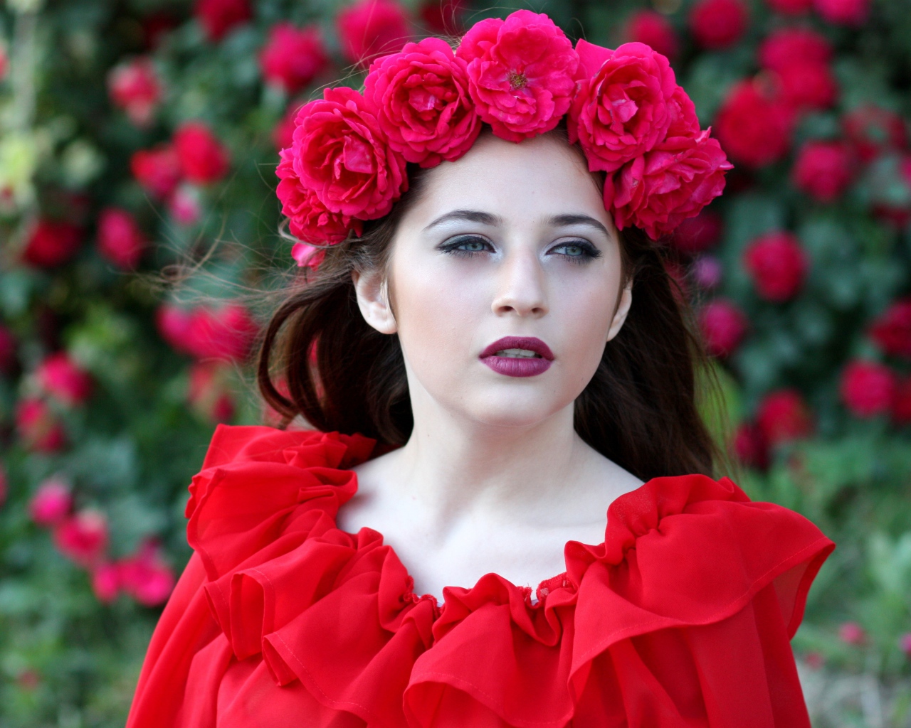 Яркая девушка в красном платье с венком из роз на голове