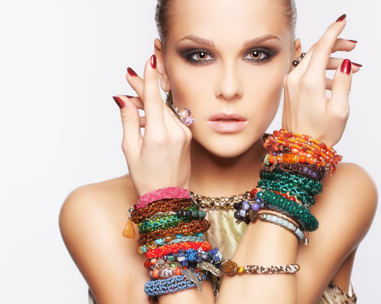 Кареглазая девушка с браслетами на руках на белом фоне