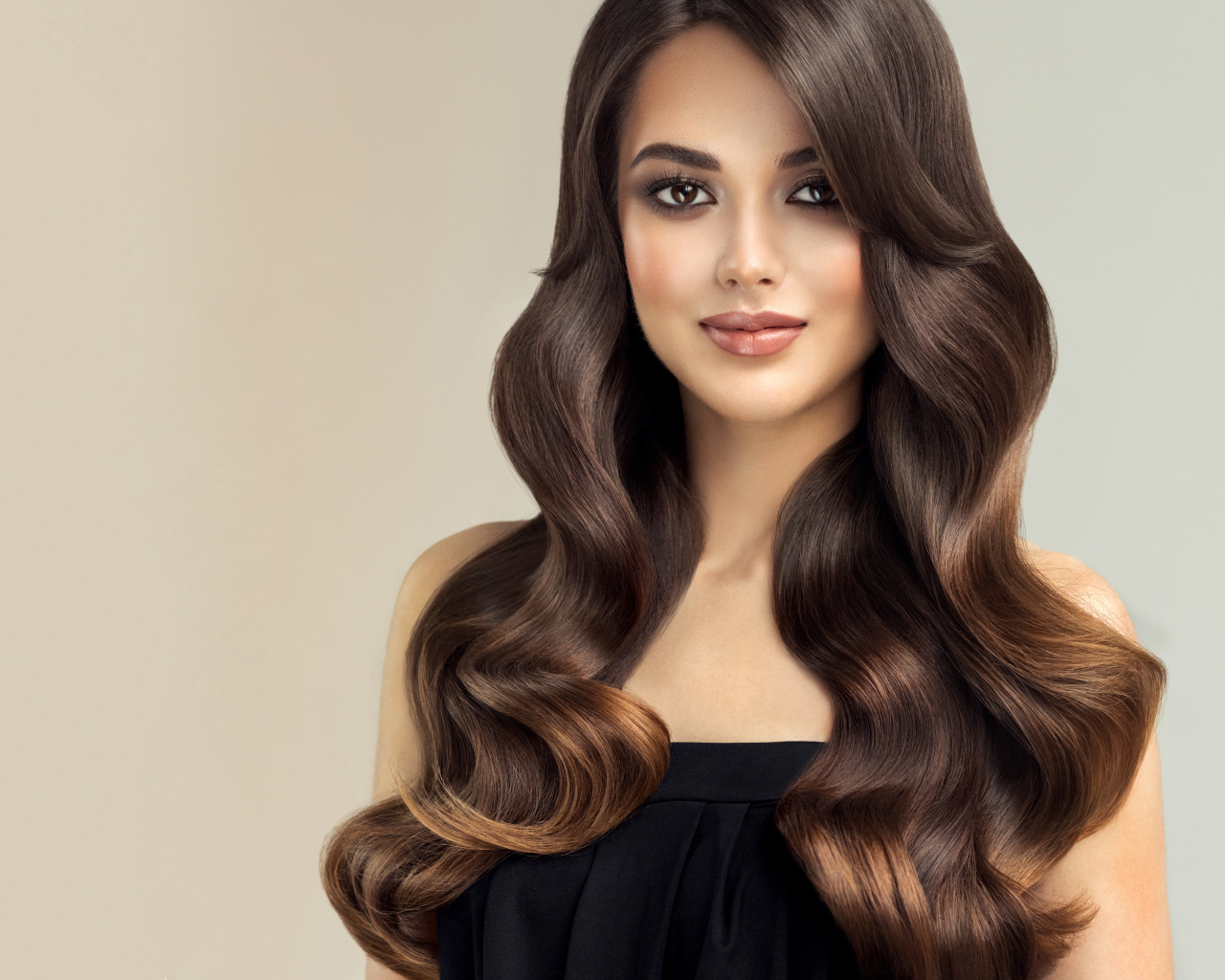 Милая кареглазая девушка с красивыми длинными волосами на сером фоне