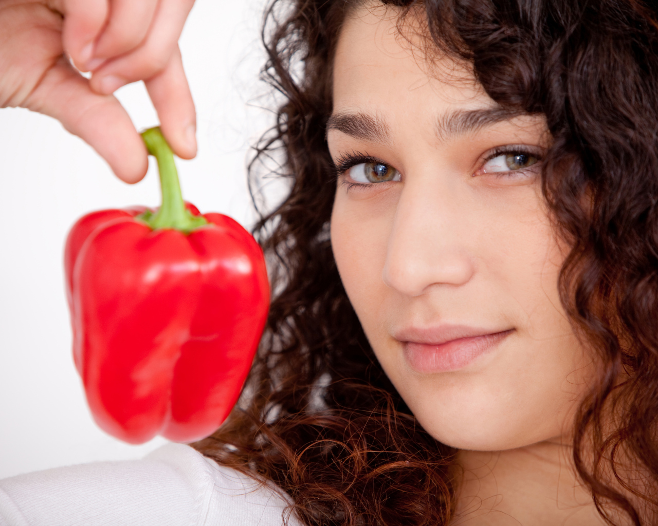 Лицо девушки с красным сладким перцем в руке крупным планом