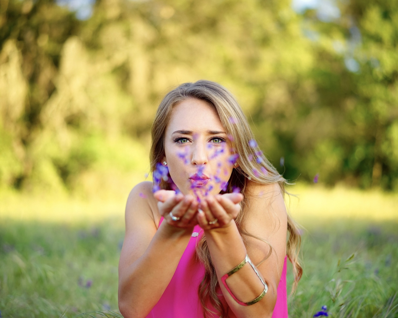 Девушка сдувает лепестки с ладоней 