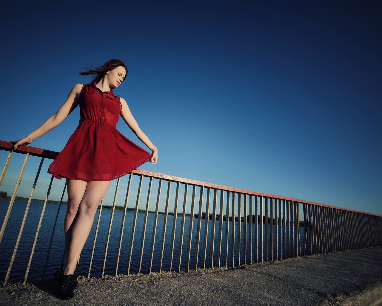 Девушка в коротком красном платье на мосту 