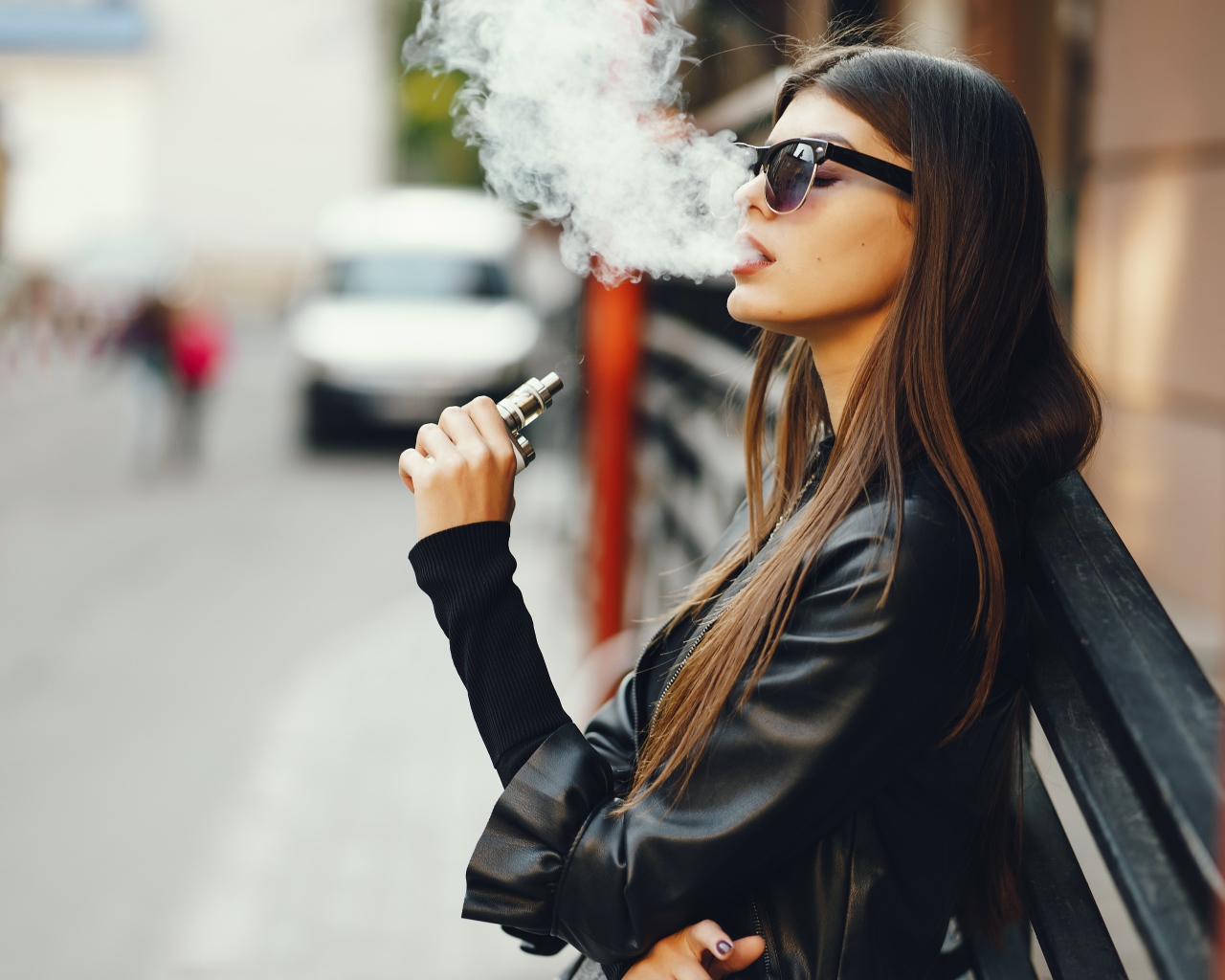 Девушка в солнечных очках пускает дым со рта