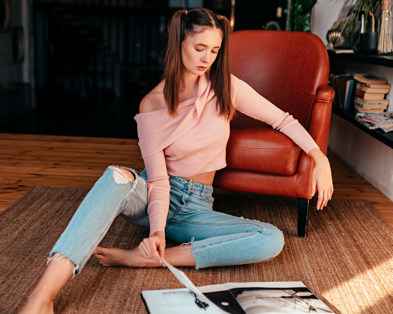 Девушка читает журнал на полу у кожаного кресла