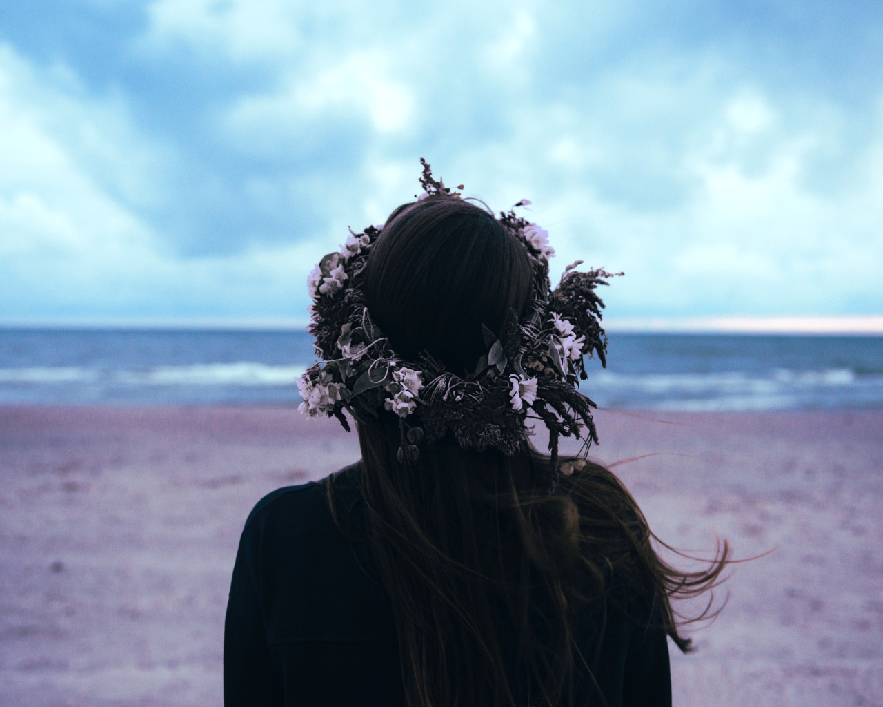 Девушка с венком на голове на фоне моря вид сзади