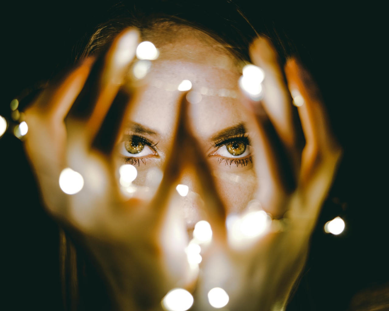 Руки с гирляндой у лица девушки