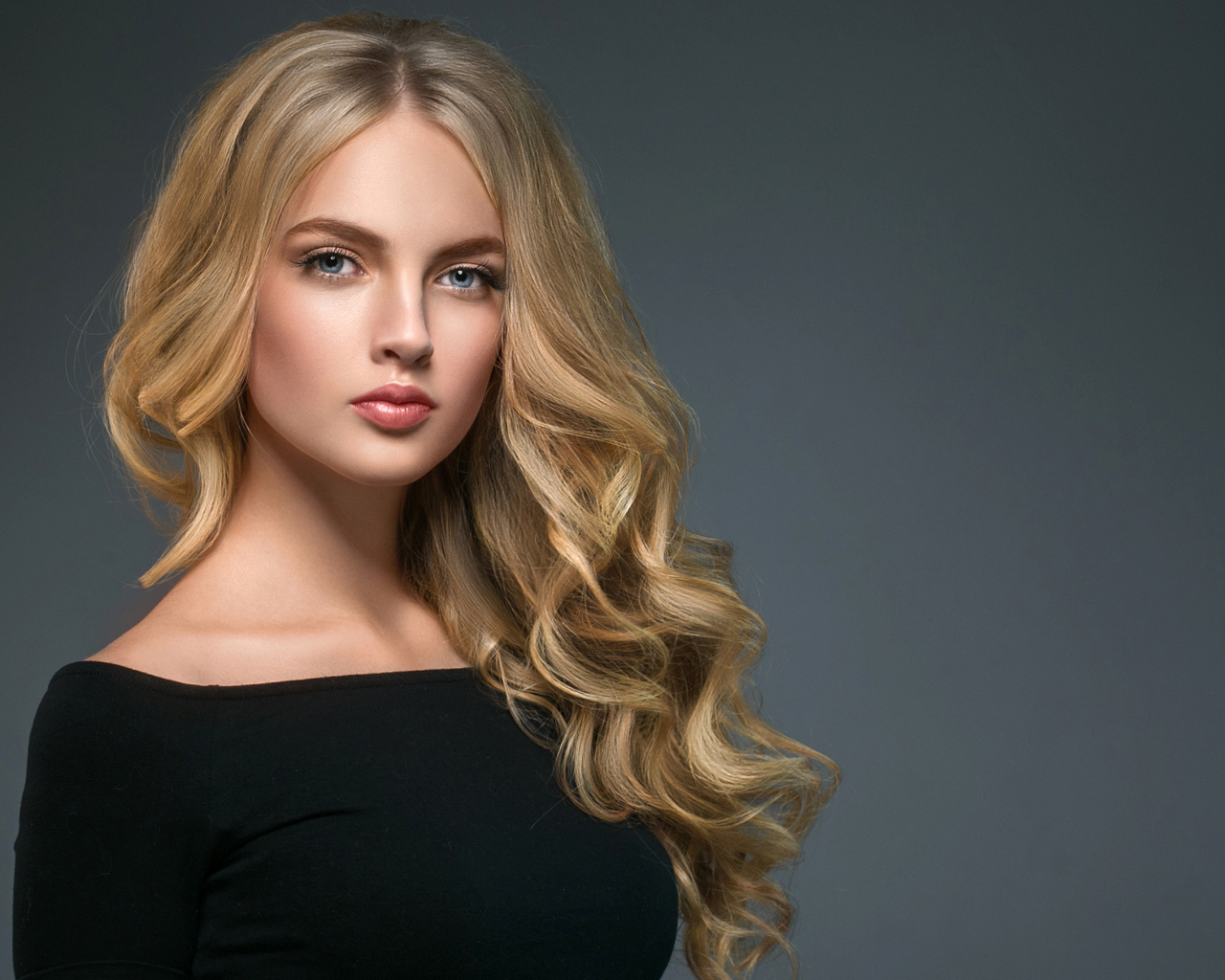 Длинноволосая блондинка с голубыми глазами на сером фоне
