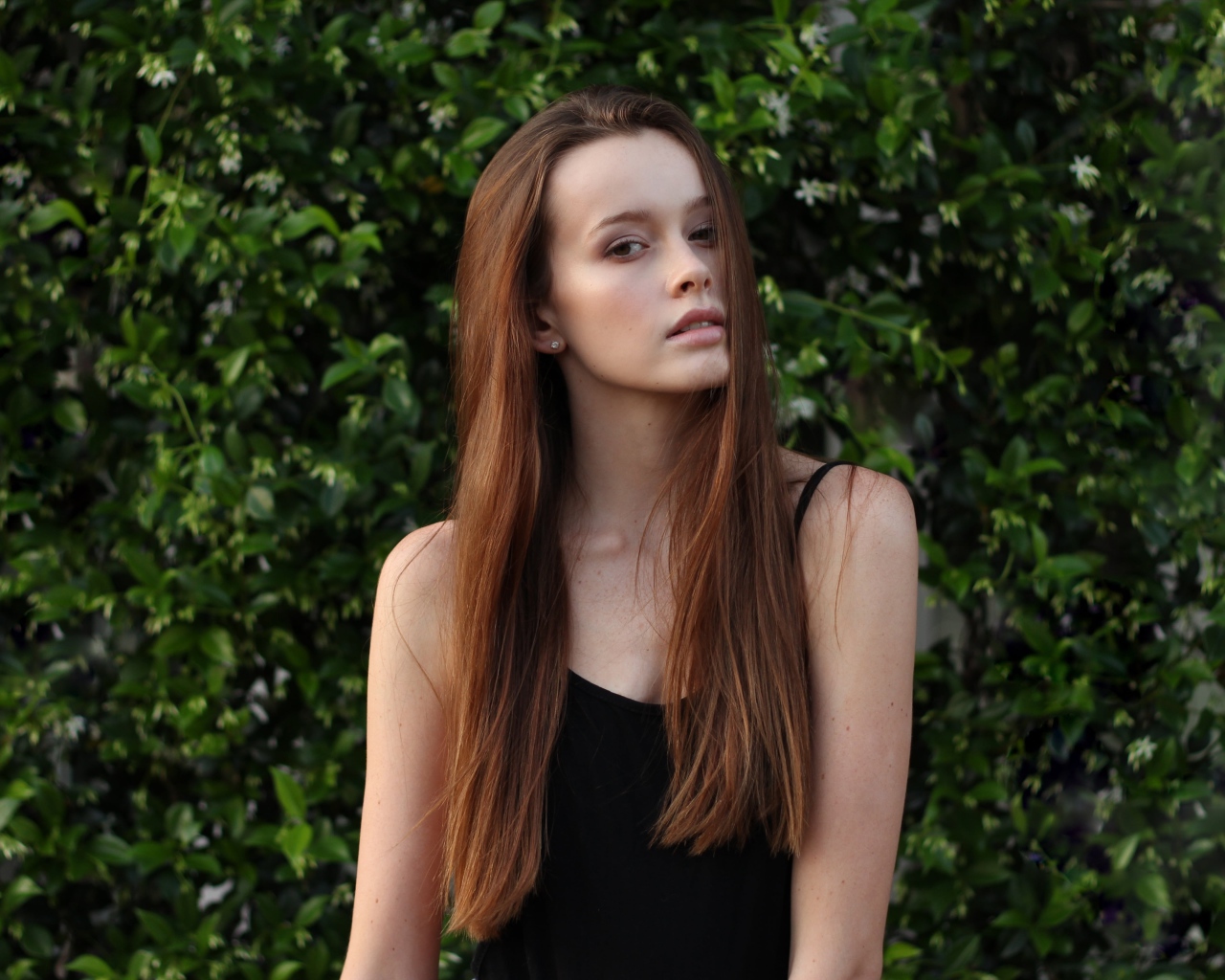 Длинноволосая шатенка на фоне зеленых зарослей