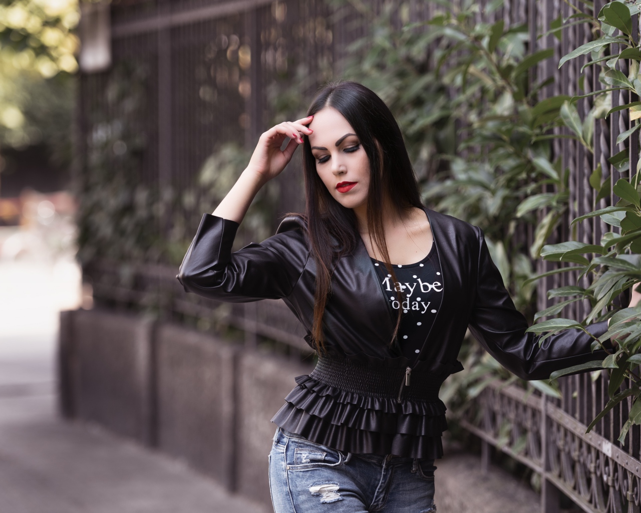 Длинноволосая брюнетка в черной куртке у забора