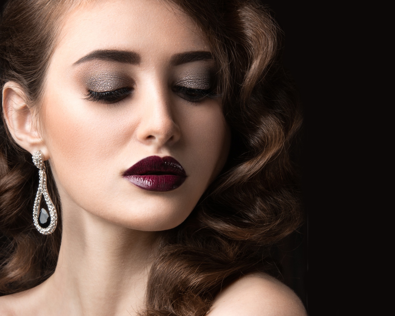 Длинноволосая девушка с ярким макияжем на черном фоне