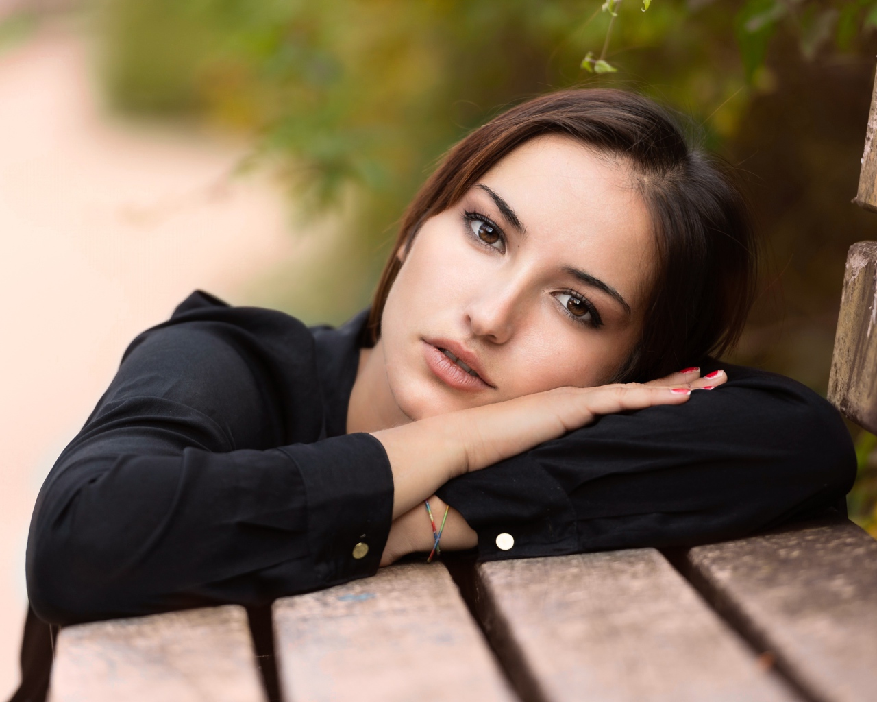 Грустная кареглазая девушка лежит на деревянной лавке