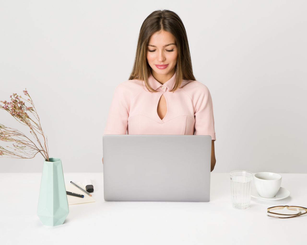 Умная девушка за ноутбуком на сером фоне