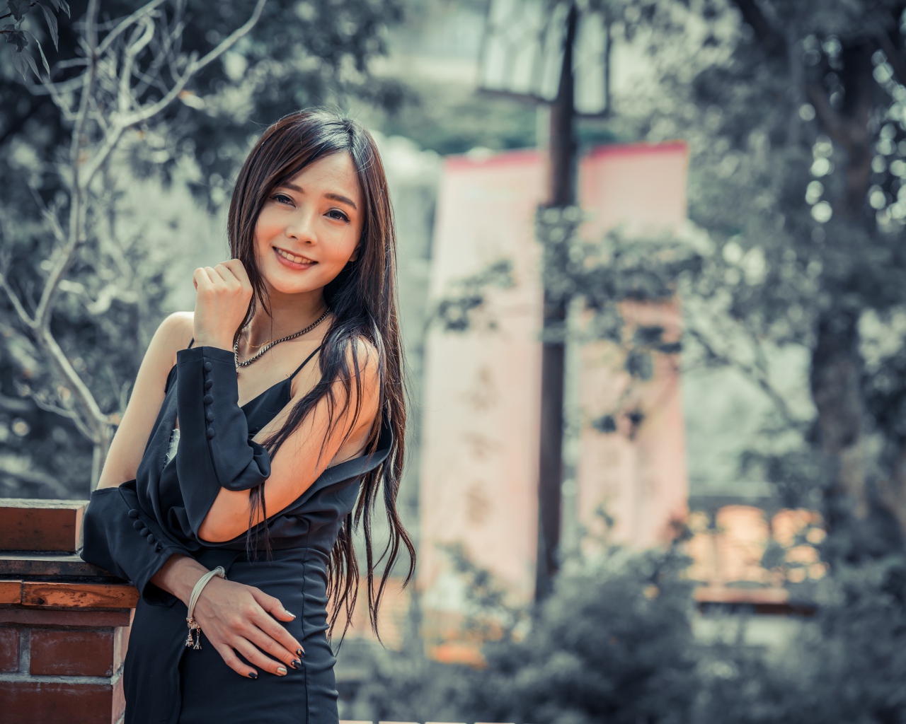 Улыбающаяся девушка азиатка в черном платье