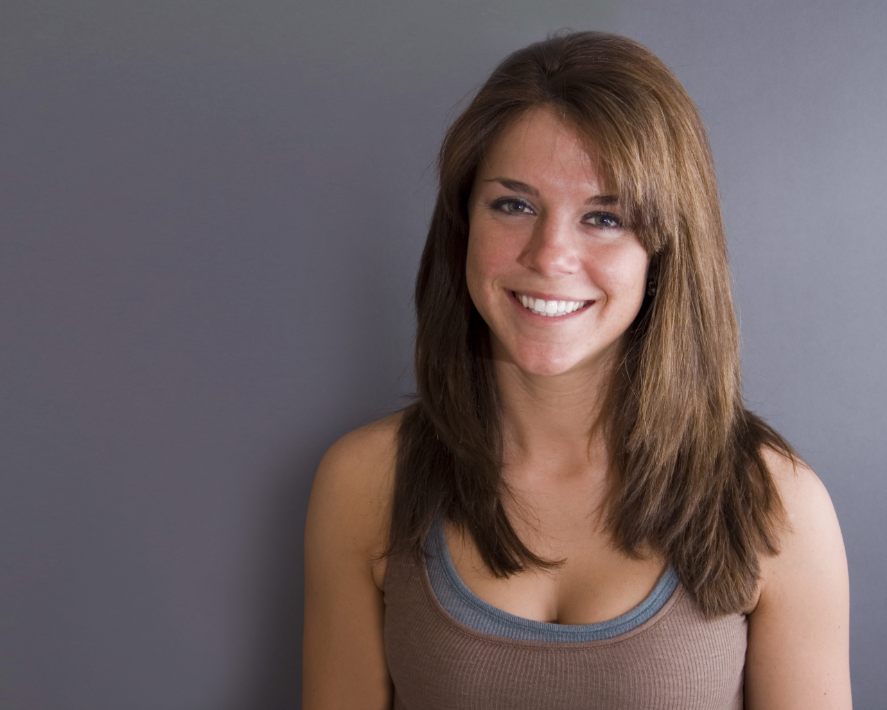 Улыбающаяся милая девушка у серой стены