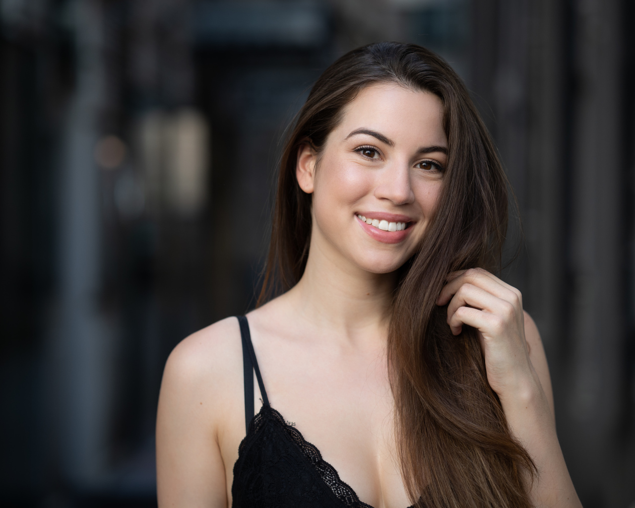 Улыбающаяся девушка держит длинные волосы