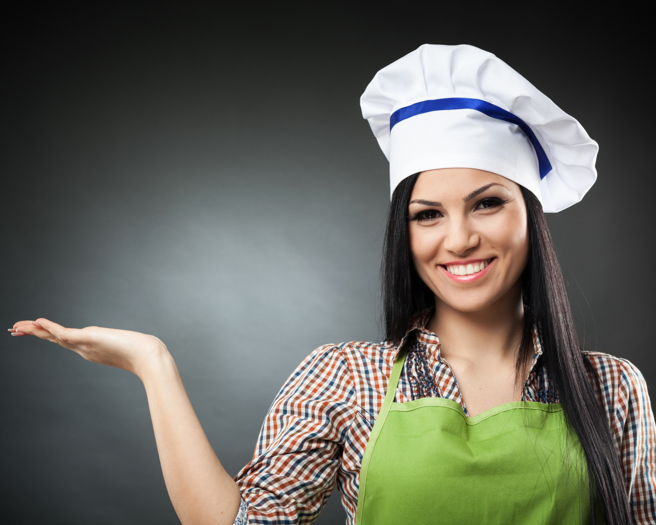 Улыбающаяся девушка в поварском колпаке на сером фоне