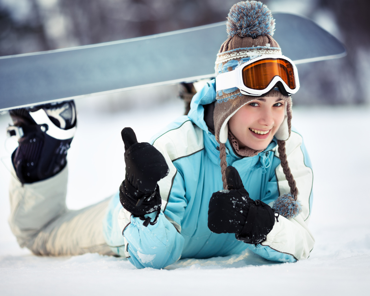 Улыбающаяся девушка сноубордистка на снегу зимой