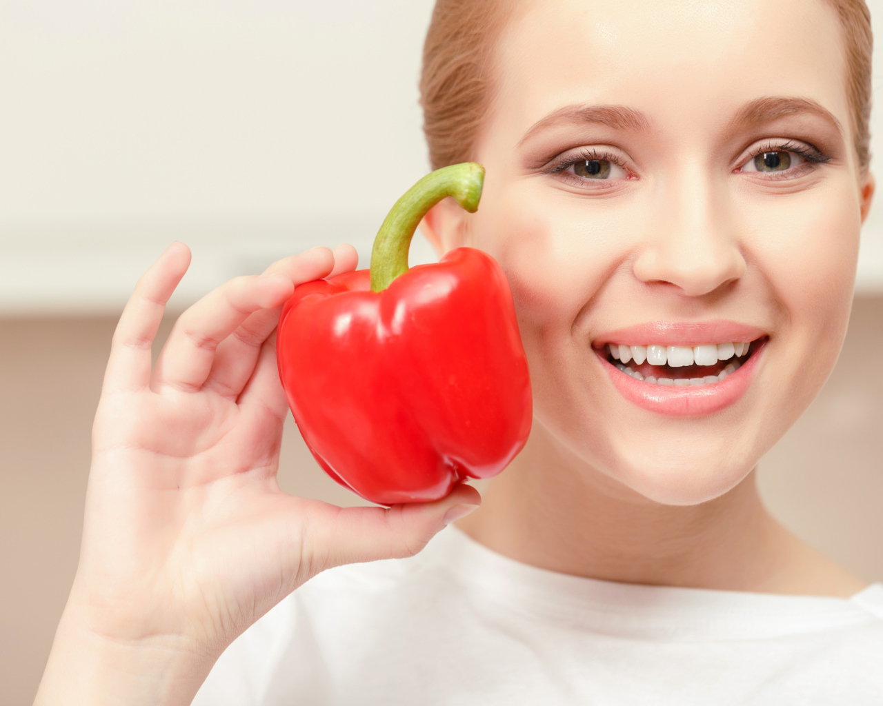 Улыбающаяся девушка с красным сладким перцем в руке