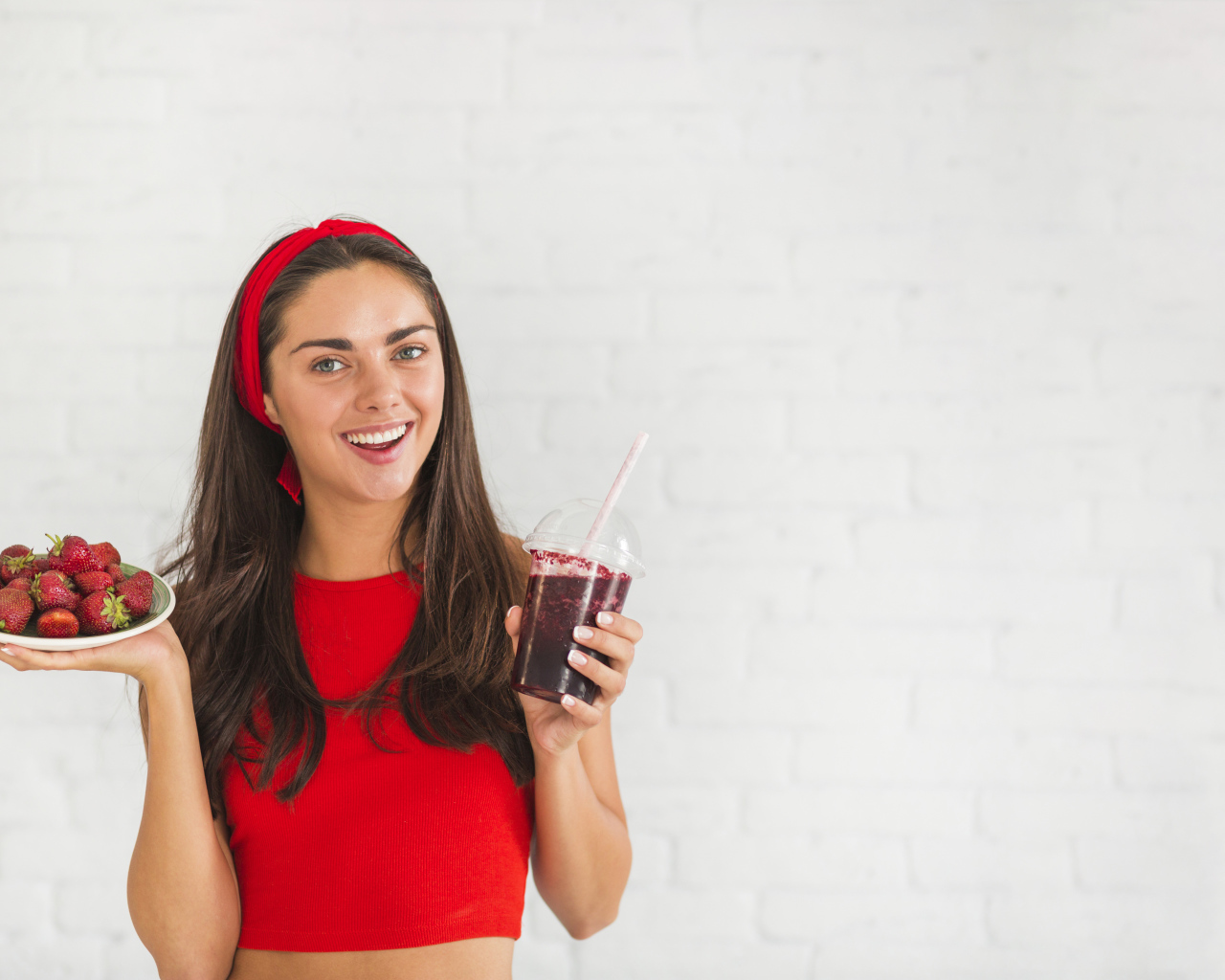 Улыбающаяся девушка с клубникой и смузи в руках