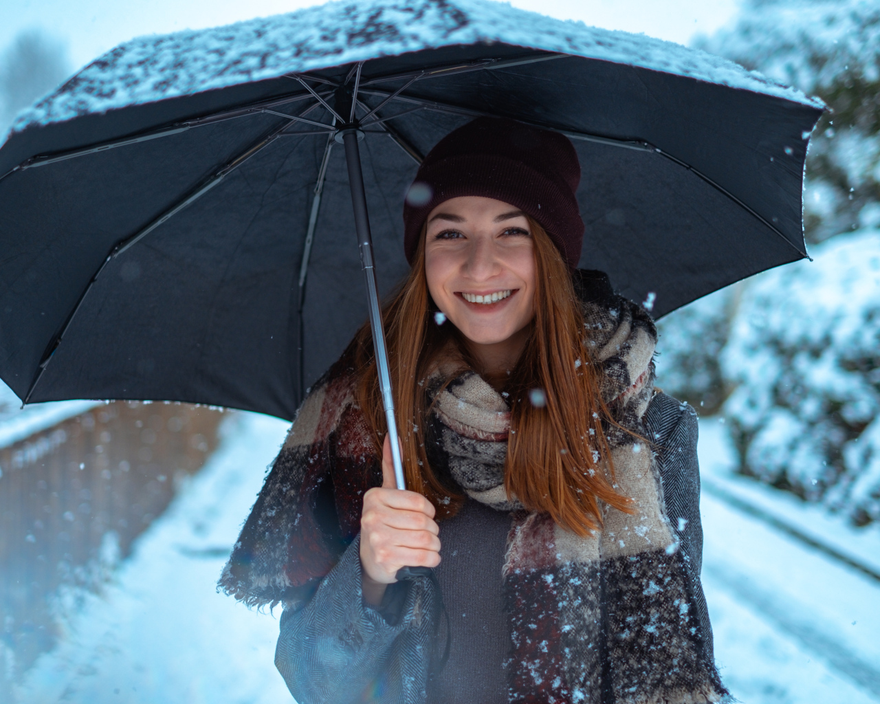 Улыбающаяся молодая девушка под зонтом зимой
