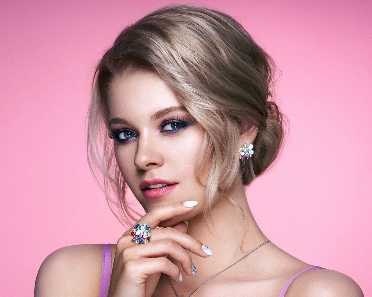 Стильная блондинка с прической на розовом фоне