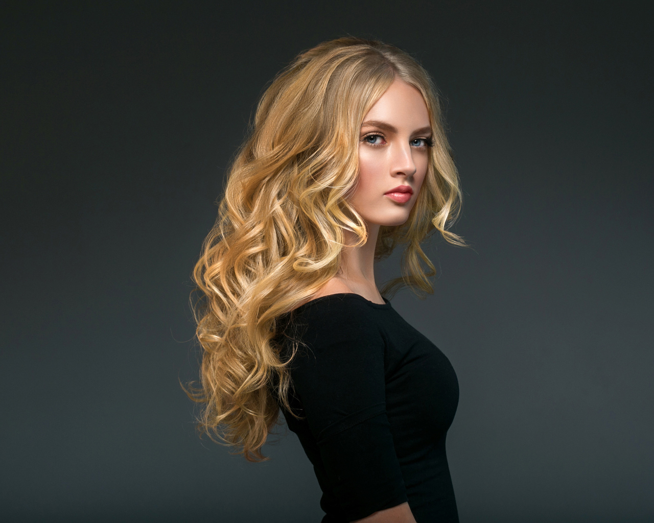 Стильная голубоглазая длинноволосая девушка в черном наряде