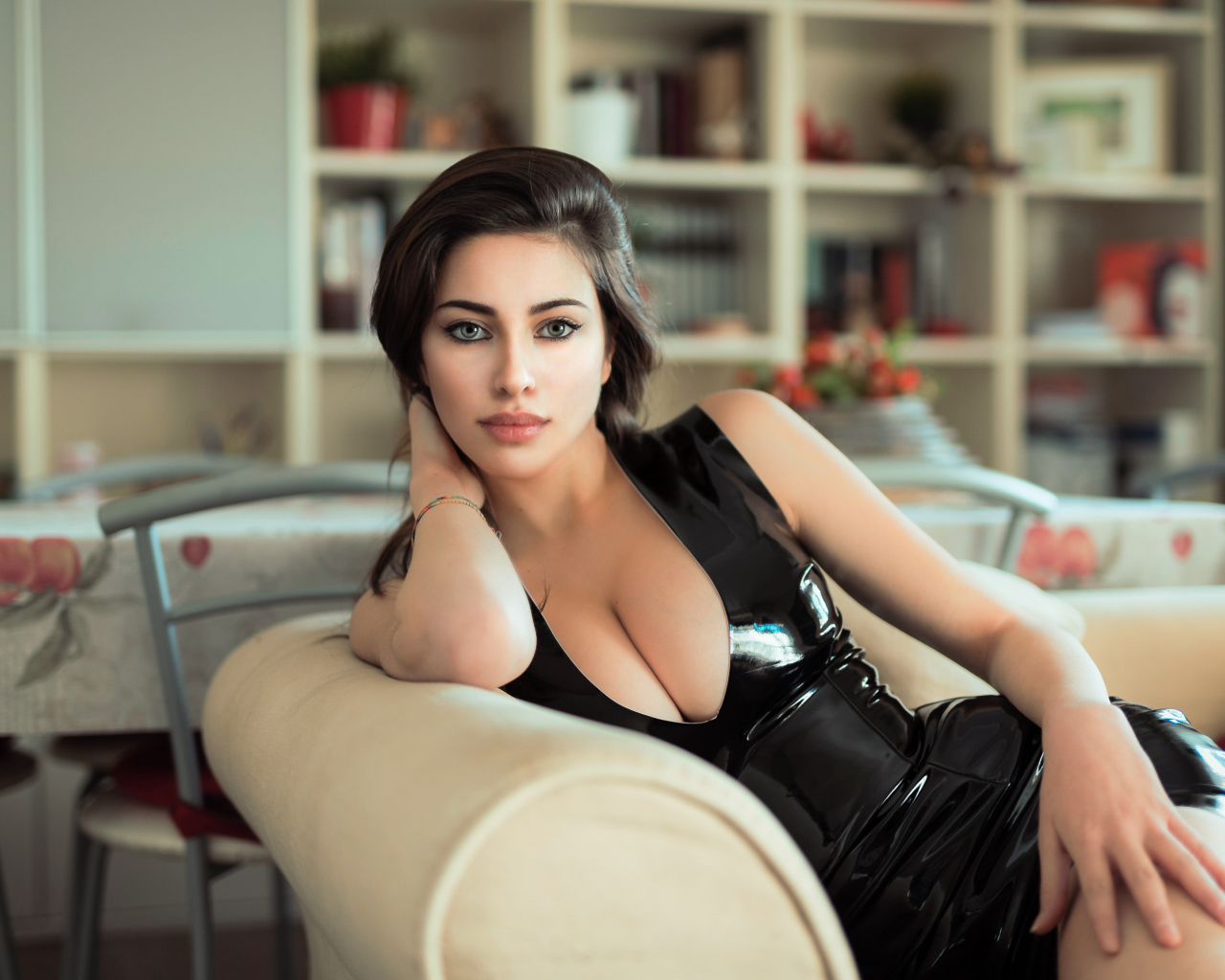 Стильная модная девушка в черном платье на диване