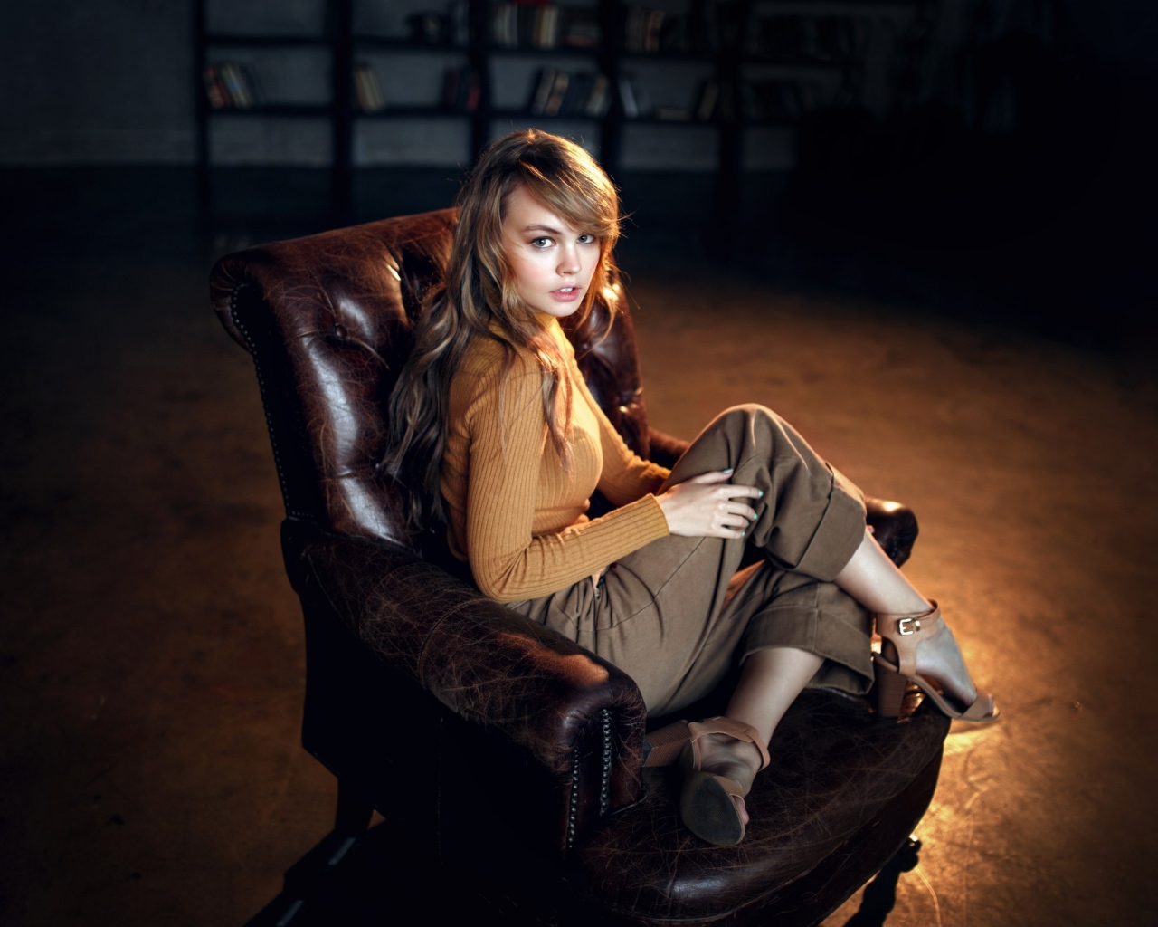 Нежная девушка модель сидит в кожаном кресле