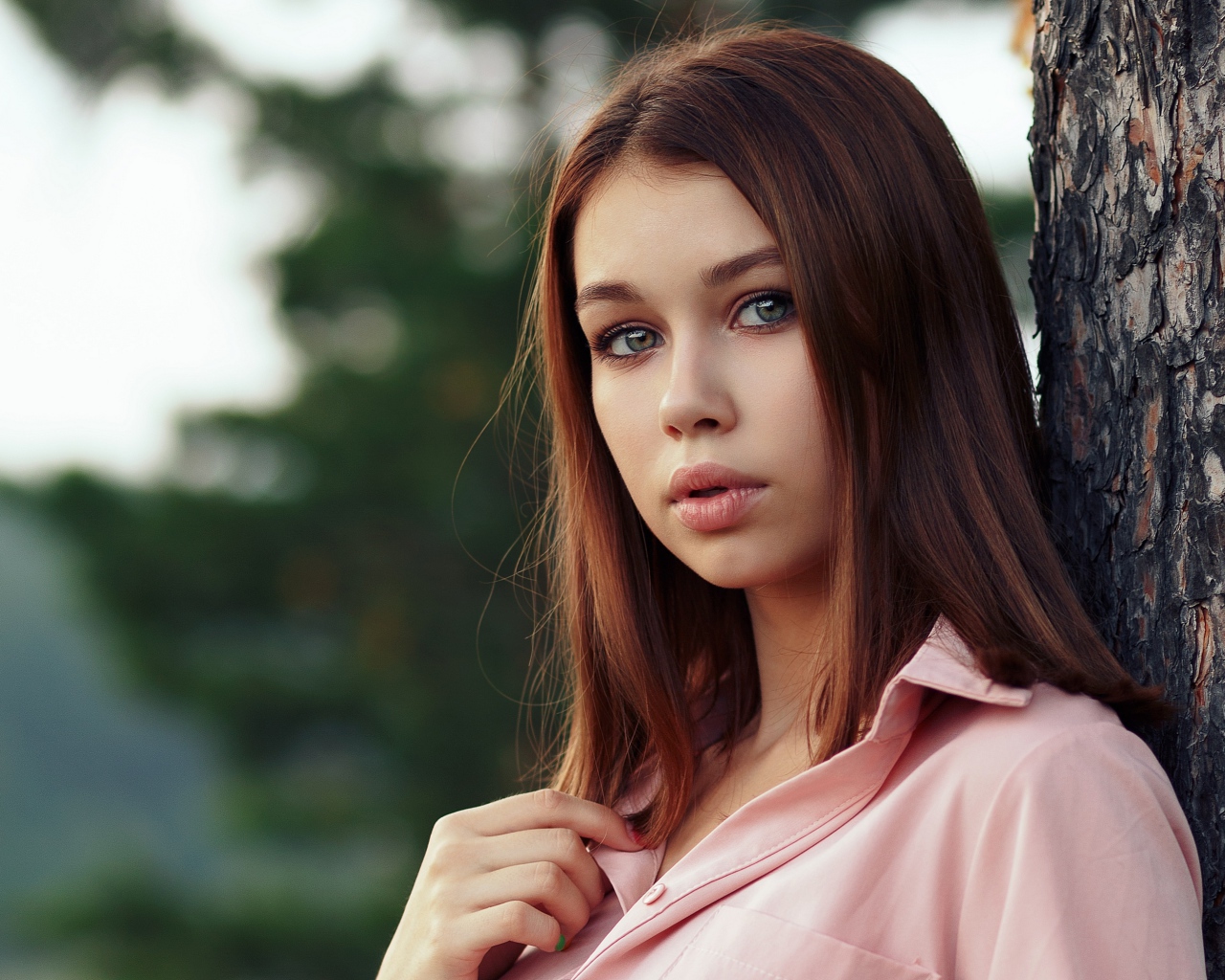 Нежная девушка стоит у дерева