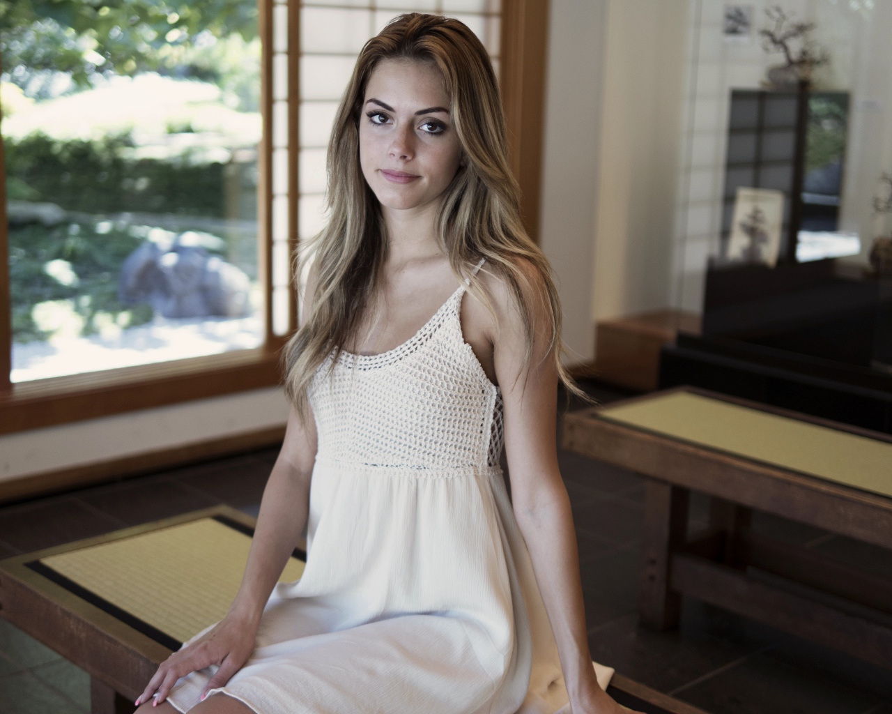 Девушка в белом сарафане сидит на лавке 