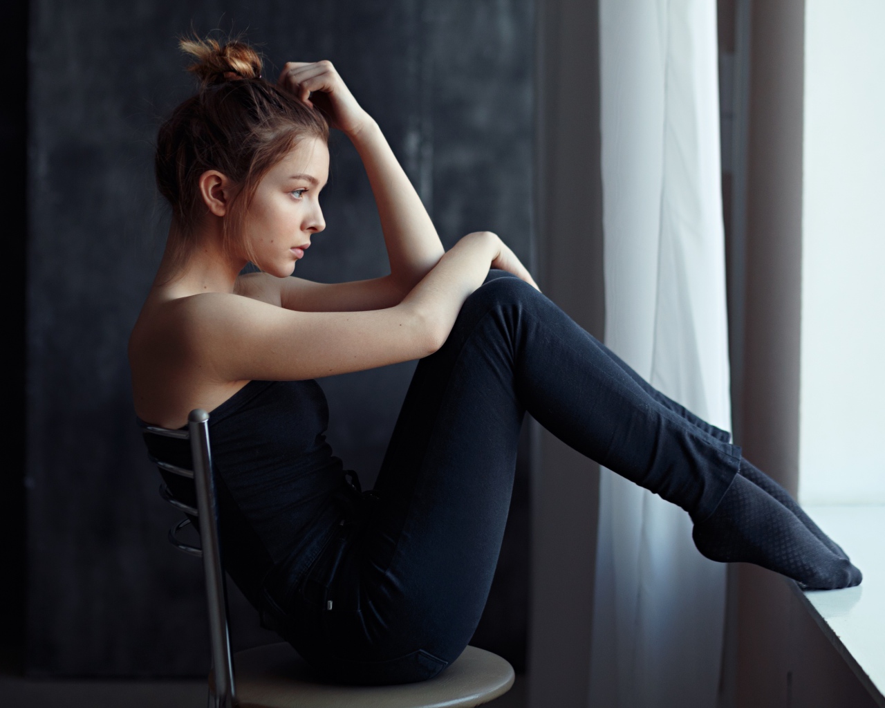 Девушка в черном наряде сидит на стуле