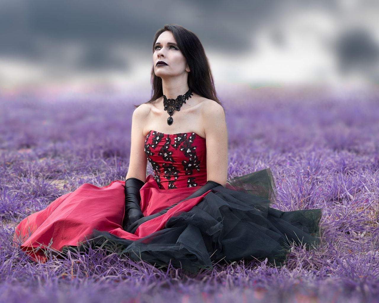 Девушка с макияжем в красивом платье сидит на траве