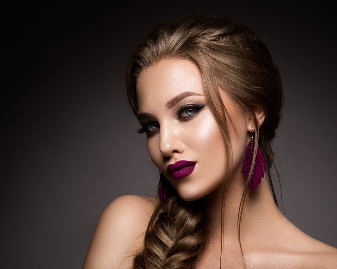 Девушка с ярким макияжем и косой на сером фоне