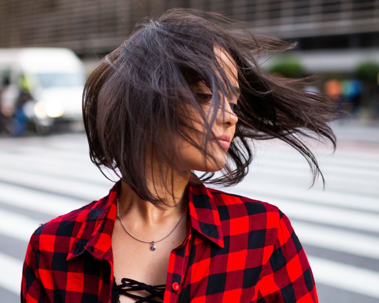 Ветер развивает волосы красивой шатенки в клетчатой рубашке