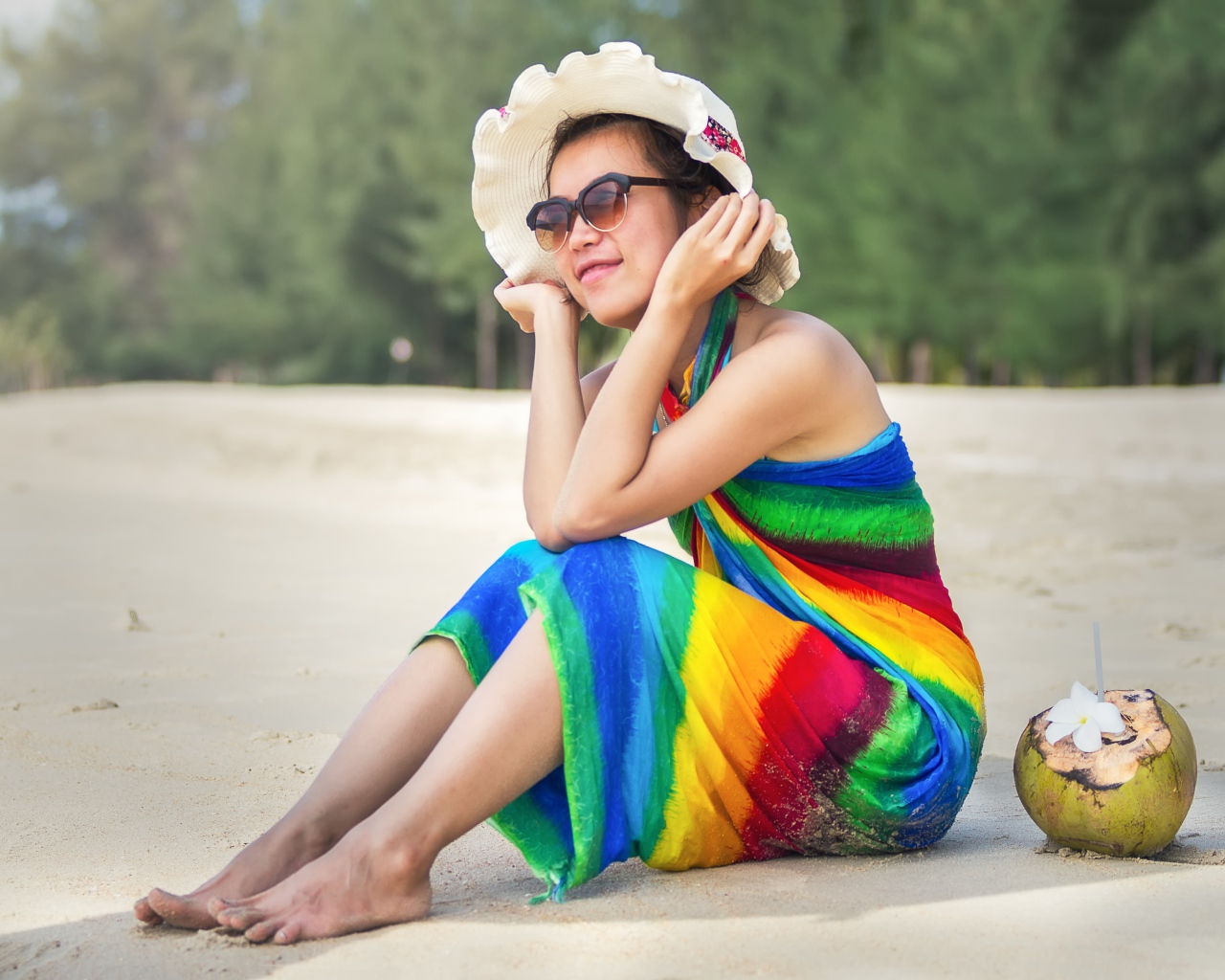 Молодая азиатка сидит на берегу с кокосом