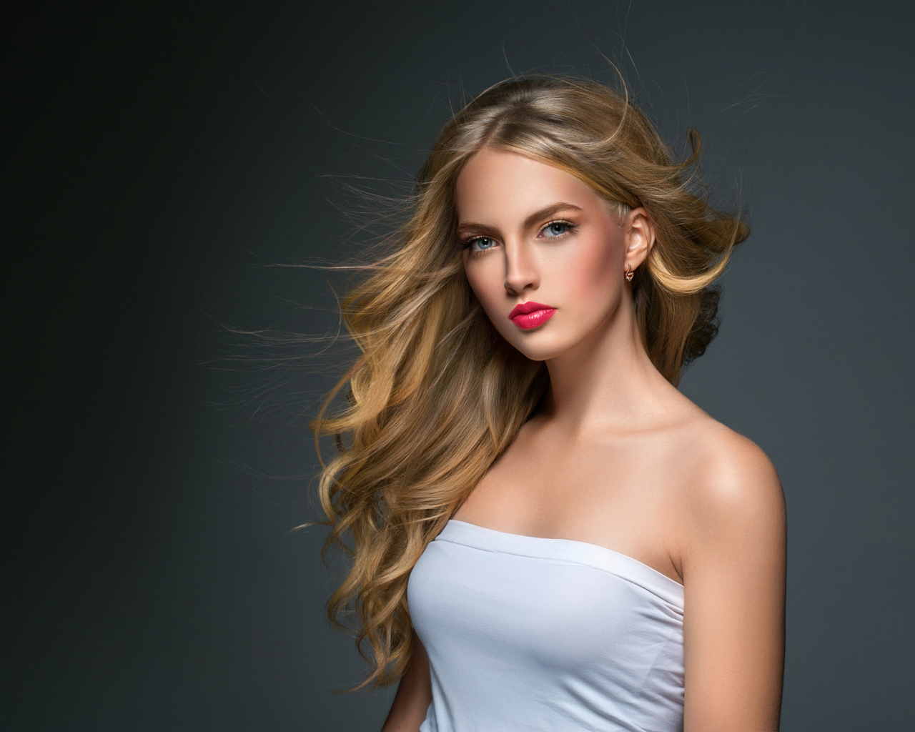 Молодая красивая голубоглазая блондинка на сером фоне