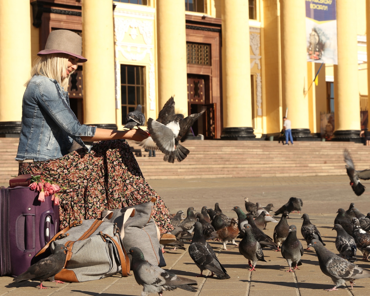 Молодая девушка кормит голубей на вокзале