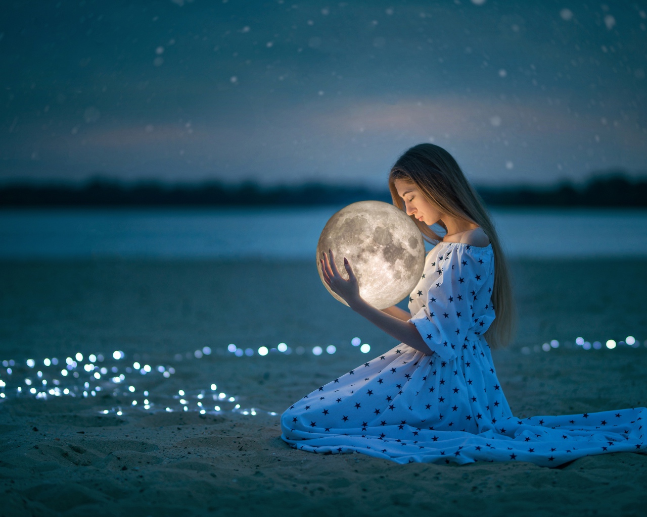 Молодая девушка в красивом платье с луной в руках на песке