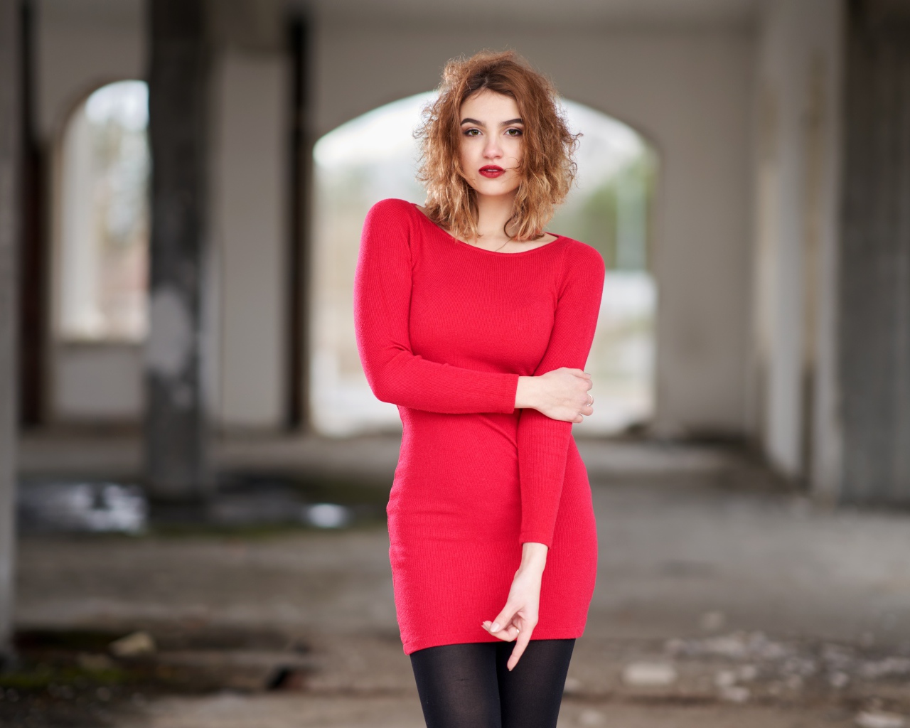 Молодая девушка в красном платье в старом здании