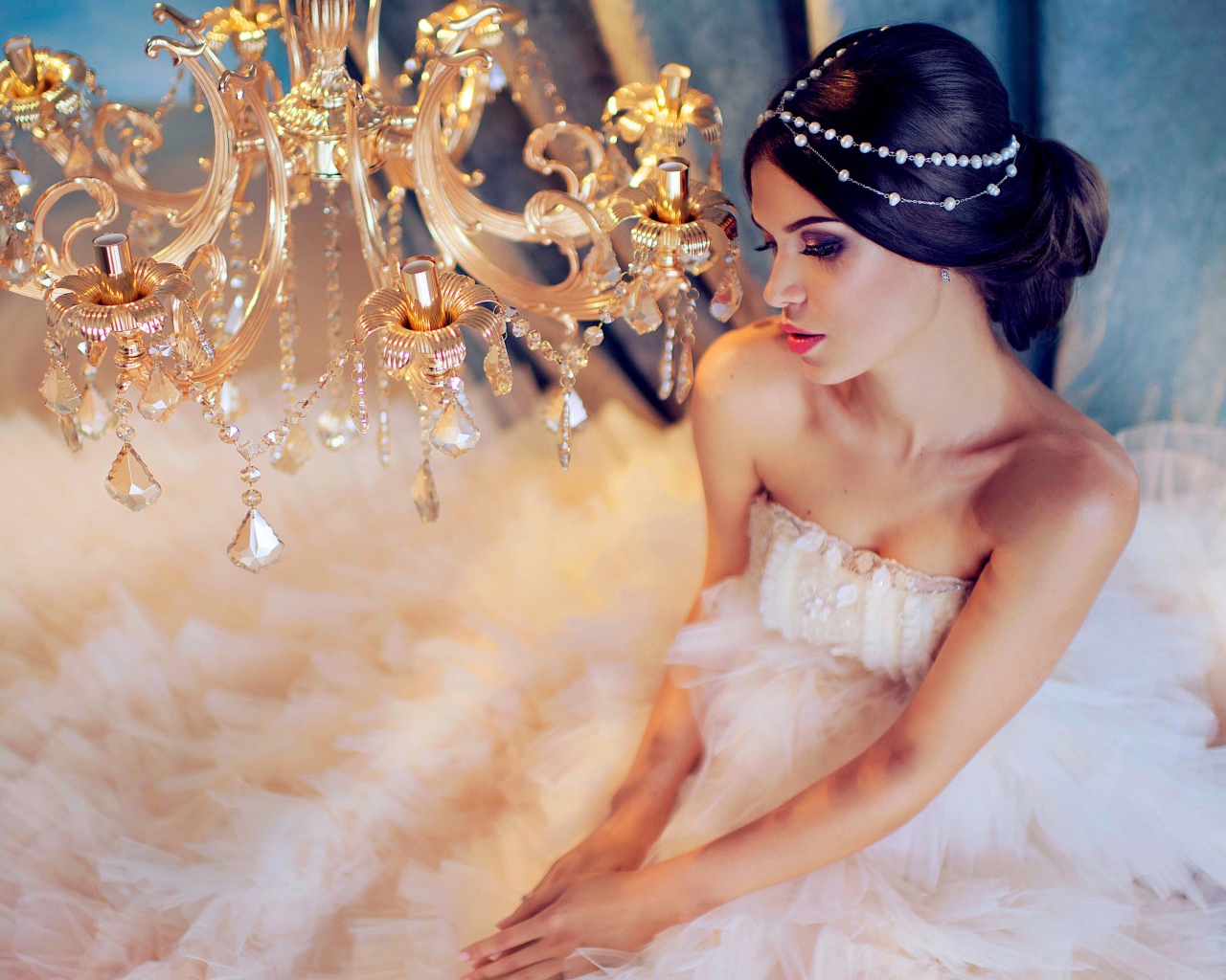 Молодая девушка в белом платье у красивой  люстры