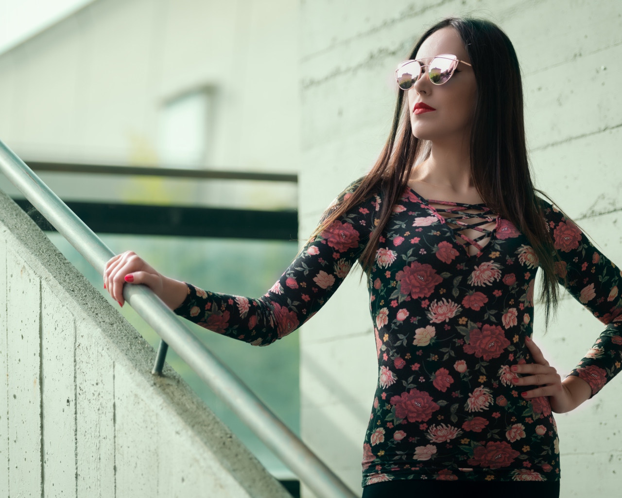 Молодая девушка в солнечных очках стоит на ступеньках
