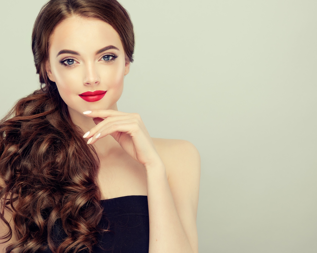 Молодая девушка с красивыми волосами на сером фоне