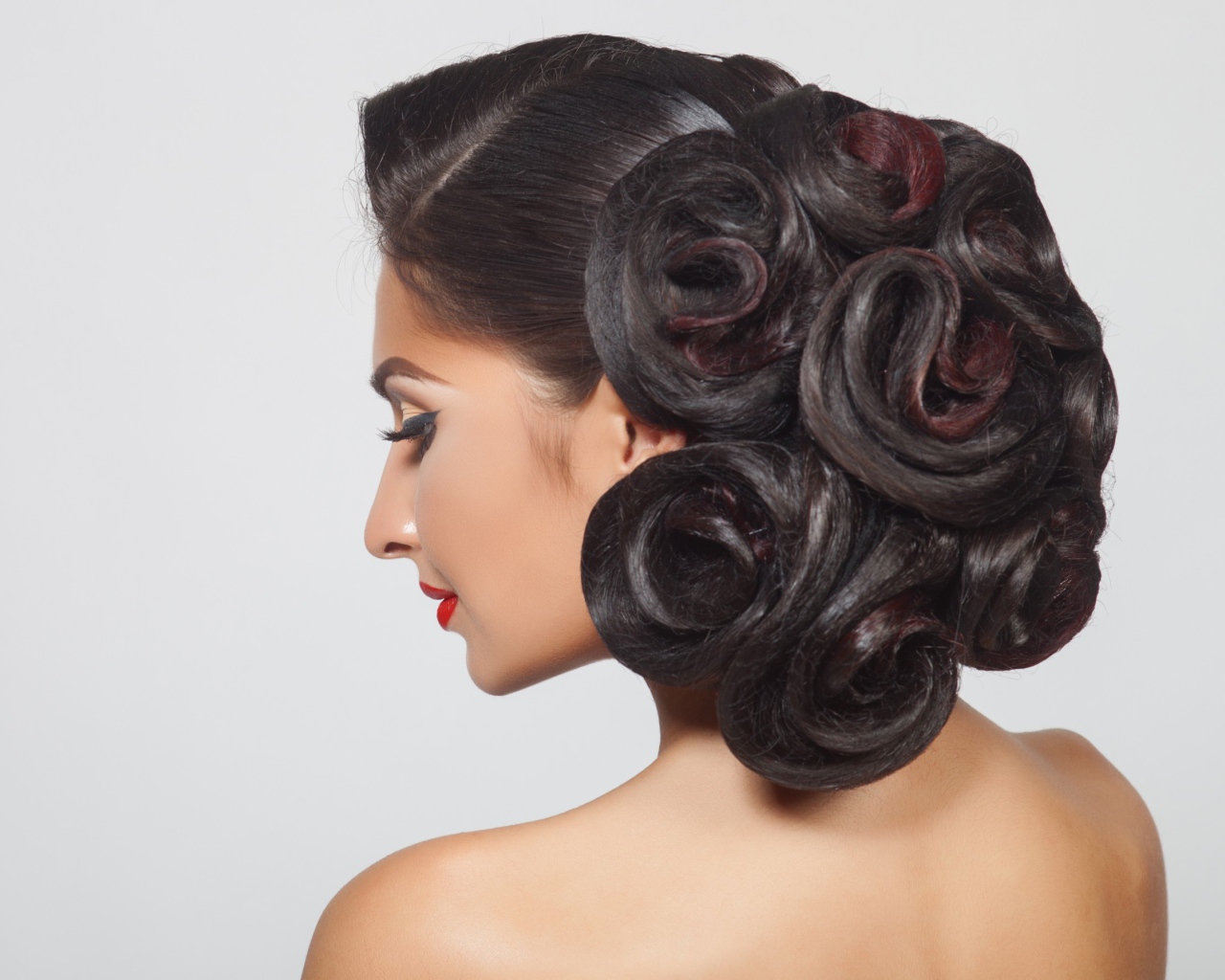 Молодая девушка с красивой прической на сером фоне