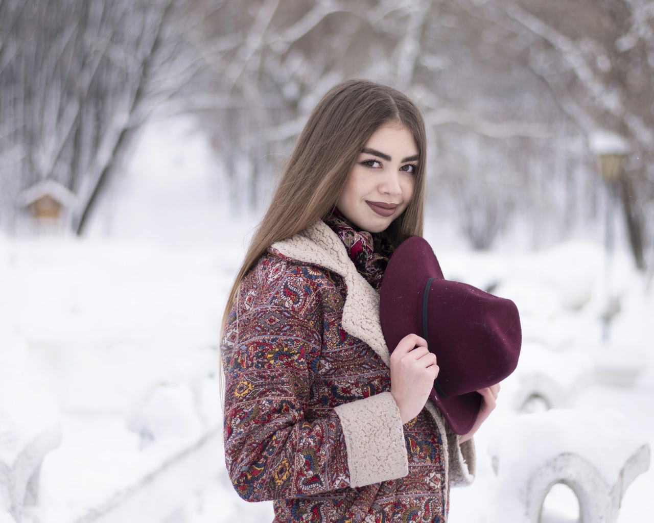 Молодая длинноволосая девушка шатенка с шляпой в руках зимой