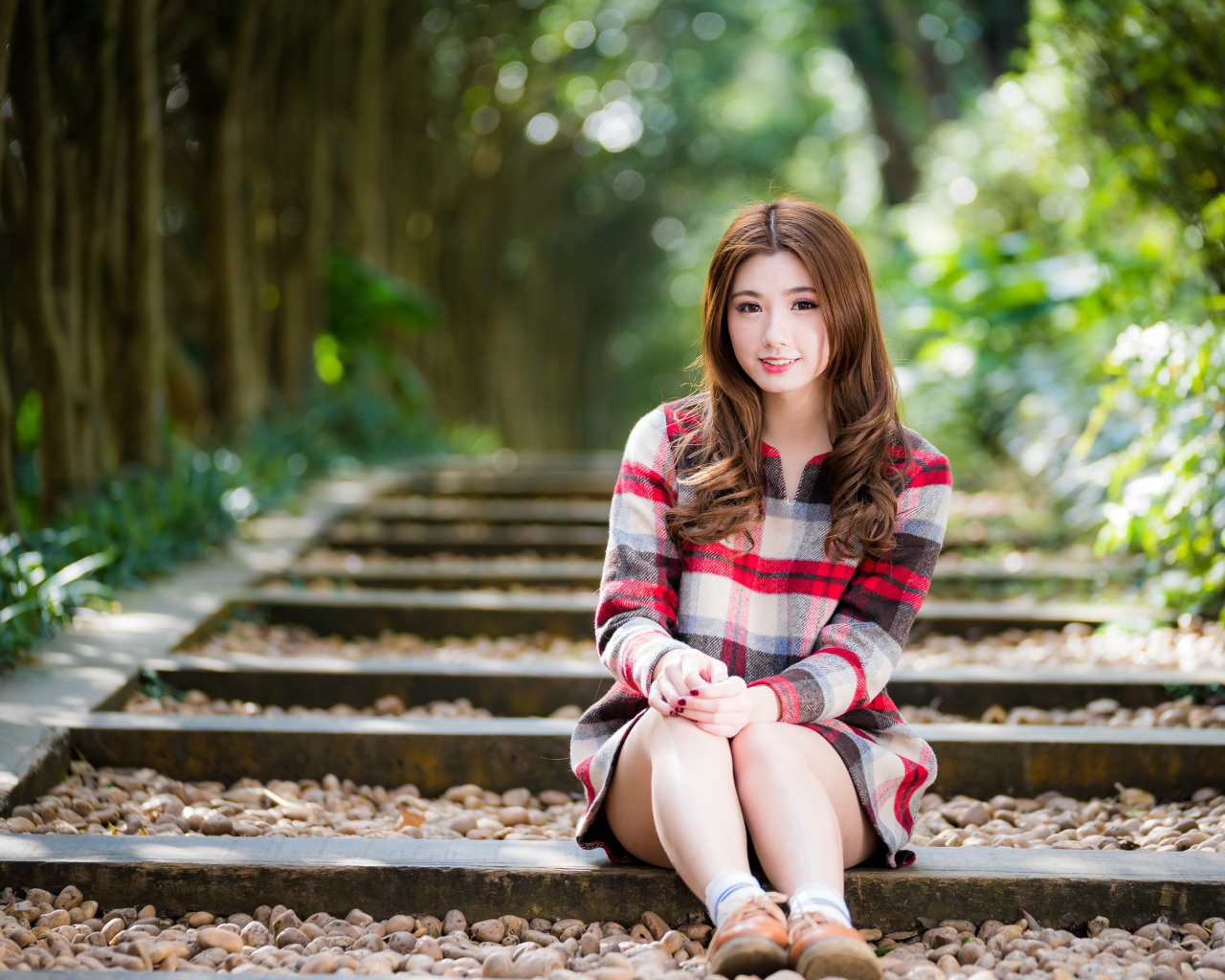 Молодая улыбающаяся азиатка сидит на дороге