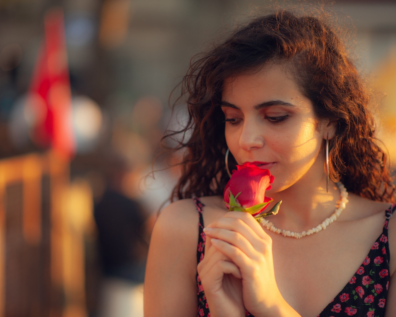 Молодая нежная девушка с красной розой в руке