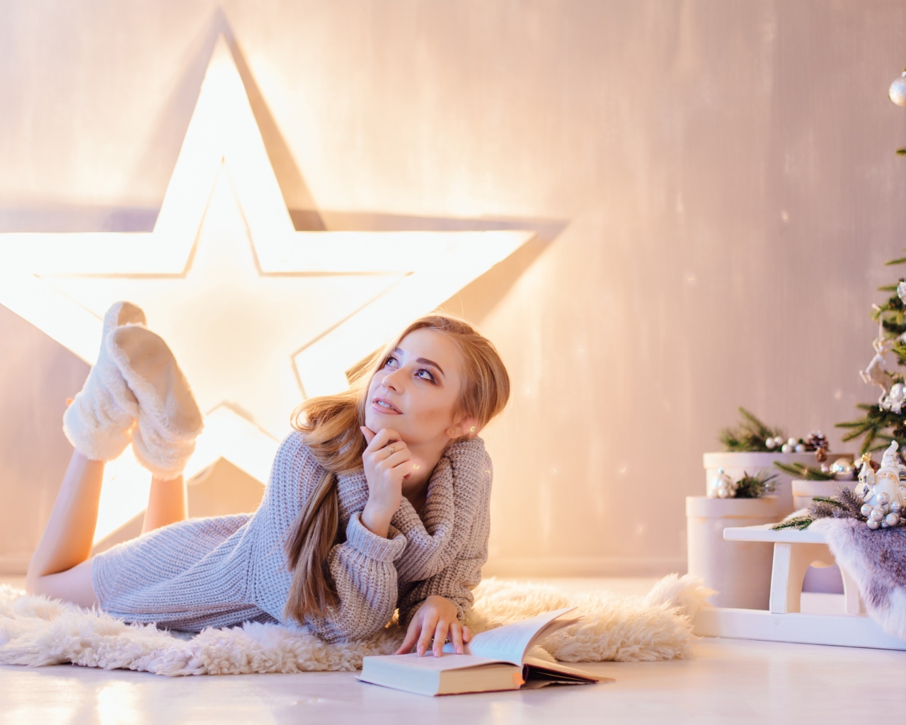 Красивая девушка читает книгу у новогодней елки