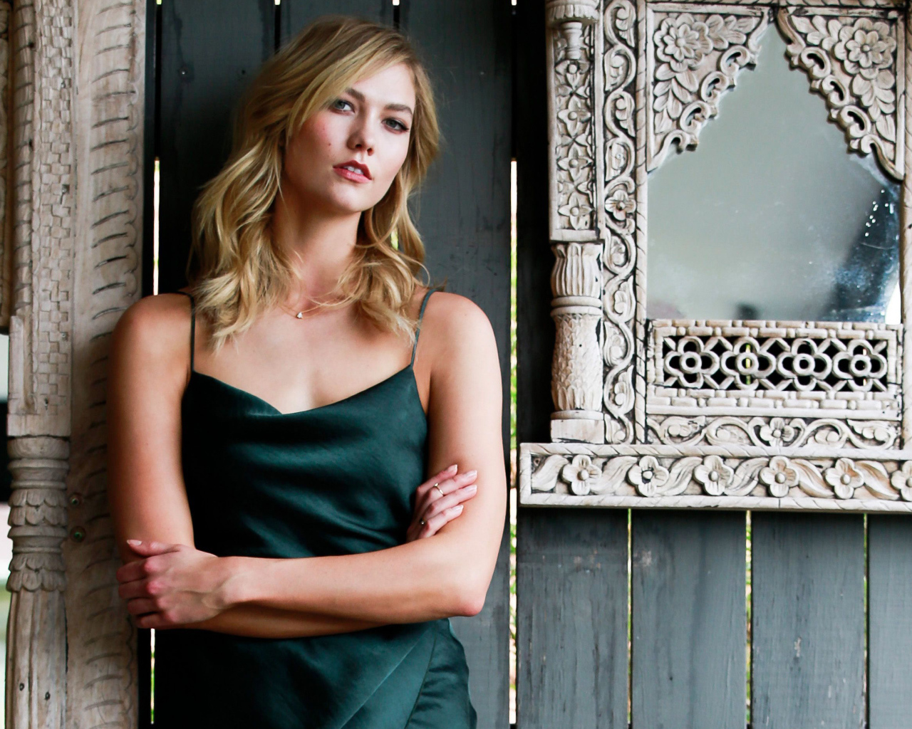 Красивая стильная модель Карли Клосс стоит у стены с зеркалом