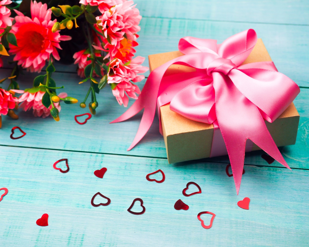 Подарок с розовым бантом на голубом столе с букетом