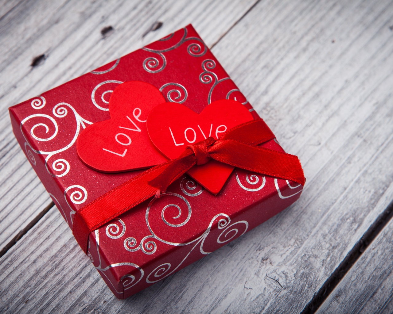 Gift with red hearts on a wooden table